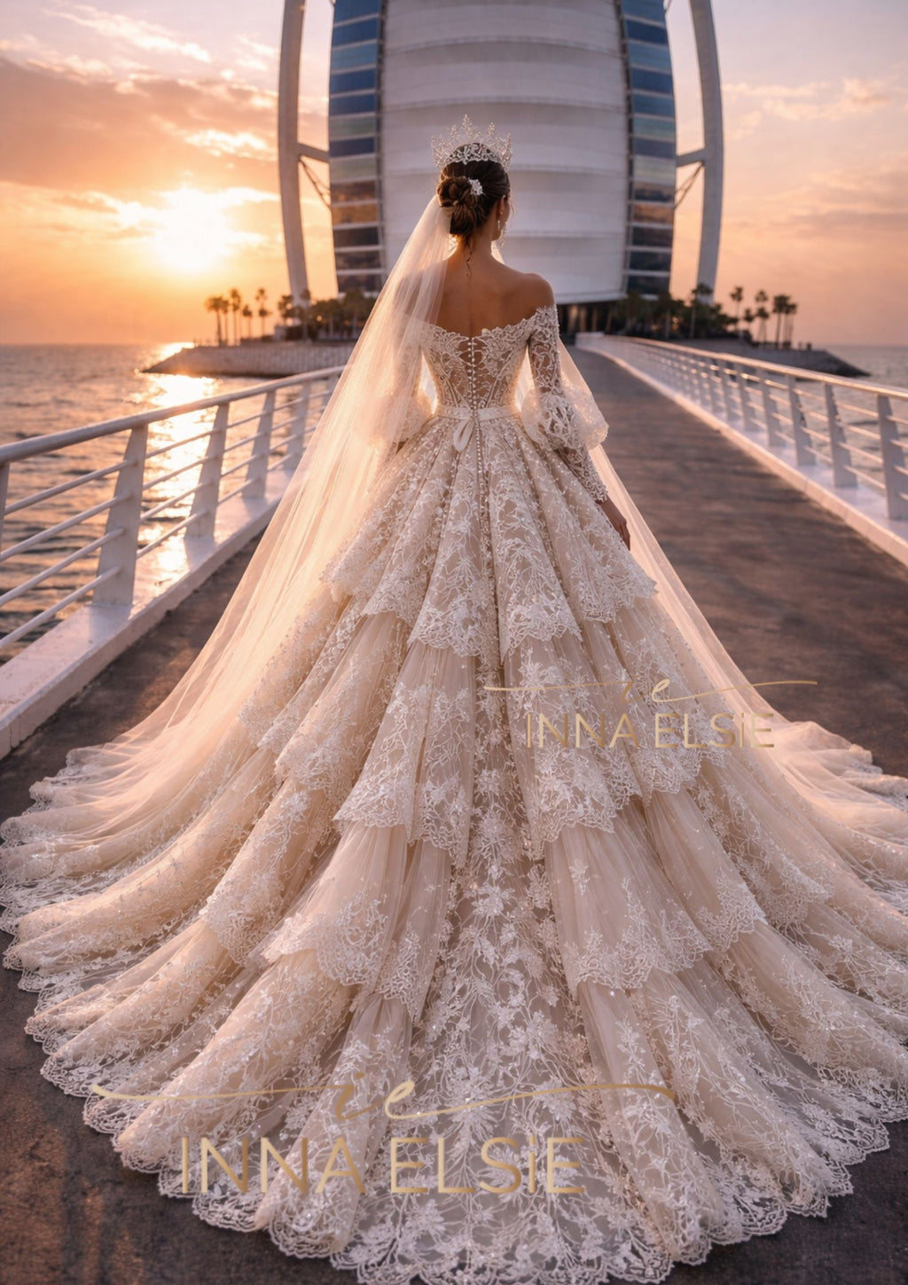 Woman in a lace wedding dress with a long train, standing on a bridge with a sunset and modern building in the background.